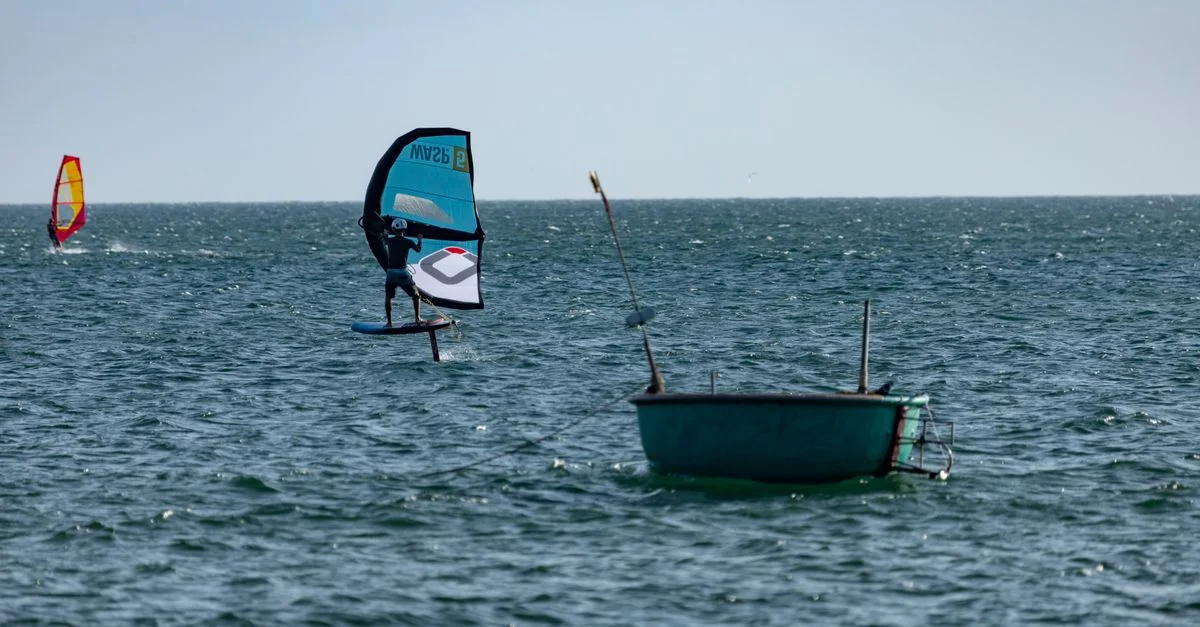 Une scène captivante de planche à voile sur la mer ouverte avec une bouée et un bateau à proximité mettant en valeur le frisson des sports nautiques.