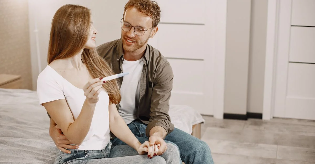 Couple joyeux vérifiant ensemble un test de grossesse dans une pièce confortable, célébrant une bonne nouvelle.