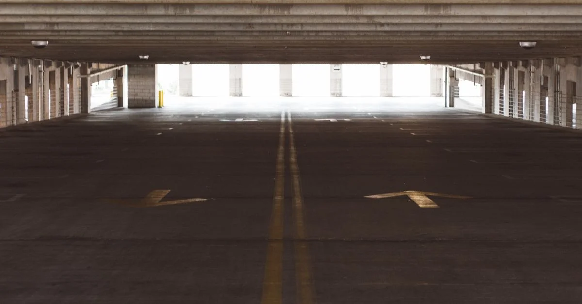 Intérieur spacieux et vide d'un garage de stationnement avec des flèches directionnelles au sol, architecture moderne.