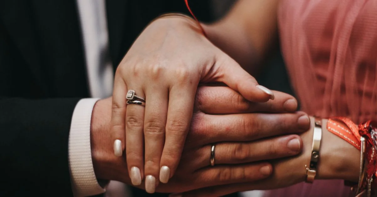 Gros plan sur les mains d'un couple avec des bagues de fiançailles, symbolisant l'amour et l'engagement.