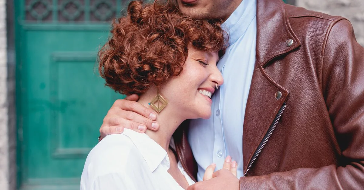 Couple heureux s'enlaçant avec des sourires, dégageant amour et chaleur en plein air.