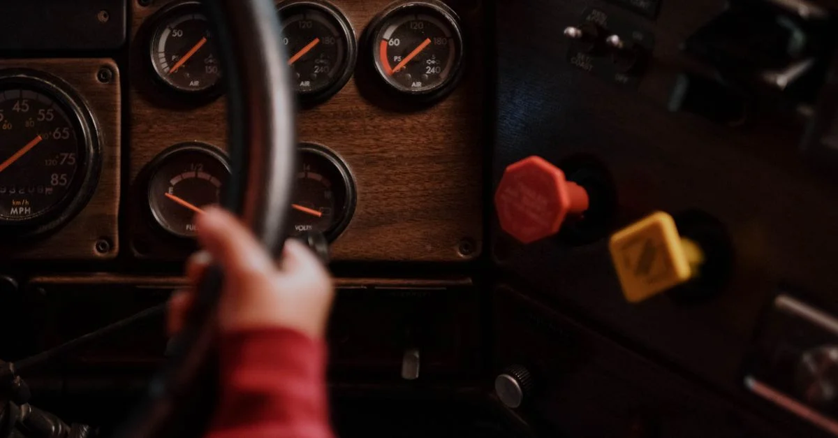 La main d'un enfant tenant un volant dans l'intérieur d'un véhicule vintage avec des cadrans.