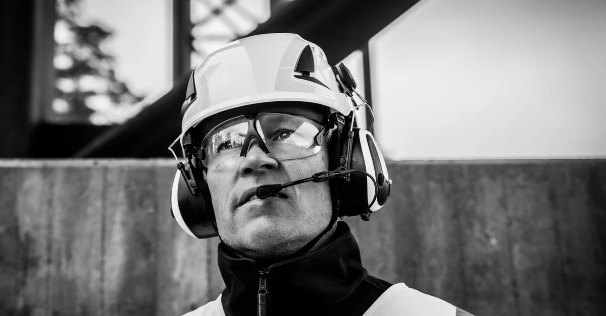 Portrait en noir et blanc d'un ouvrier du bâtiment portant des équipements de protection et un casque.